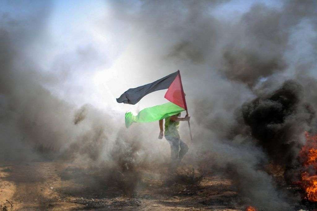 Ragazzo con la bandiera della Palestina dopo i bombardamenti
